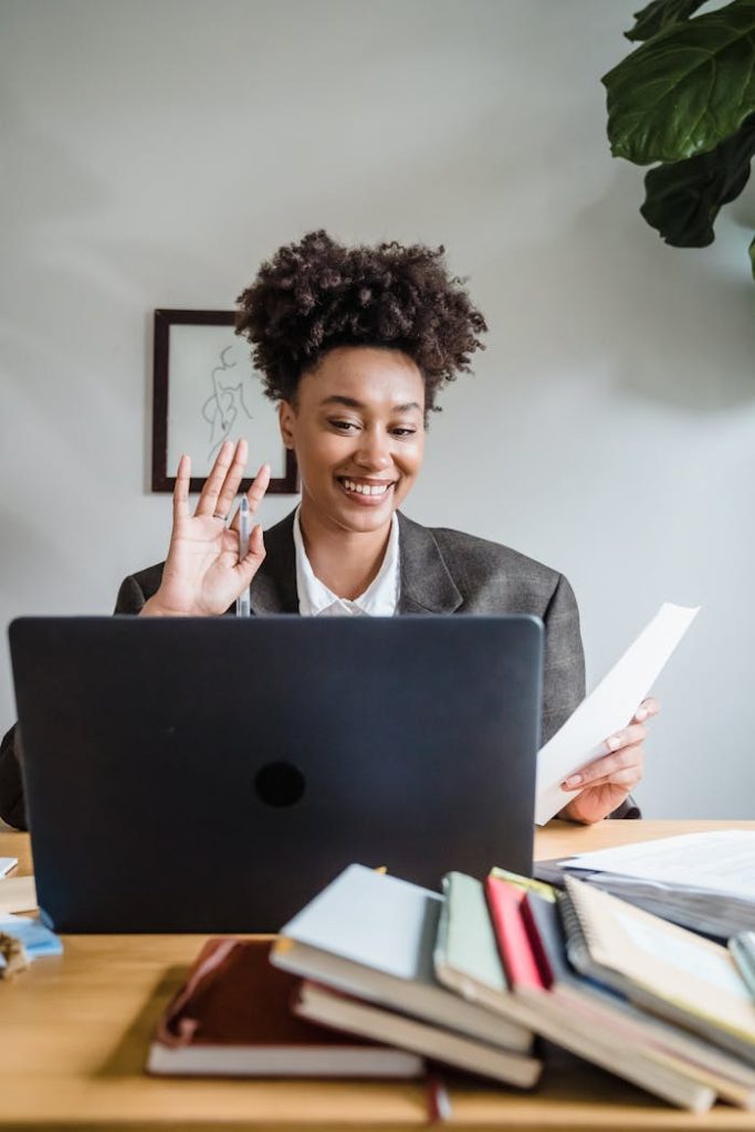 Smiling young woman working remotely, engaged in a video call from her home office.